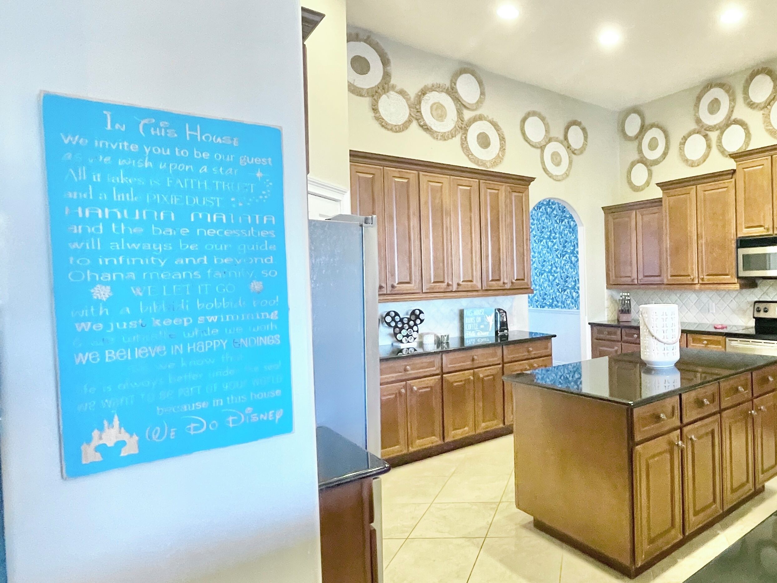 Une cuisine avec des meubles de rangement en bois, un réfrigérateur et un mur décoratif orné de motifs circulaires.