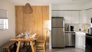 A modern kitchen with white cabinets, stainless steel appliances, and a wooden dining table set for four. - ` The Bohemian Heaven ` w/ SPA, 2miles to downtown (Naples)