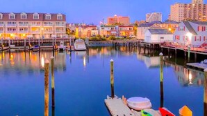 A waterfront hotel with multiple buildings, docked boats, and a calm water body reflecting the structures. - Stunning Water Views - Fireplace - Chelsea Harbor (Atlantic City)