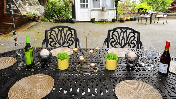 A table set outdoors with a bottle of wine, glasses, and candles. - Bodhyfryd (Penmaenmawr)