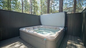 A hot tub on a wooden deck with a view of trees in the background. - Family Oasis with Access to The Cove (Sunriver)