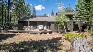 A modern house with a patio, outdoor seating, and a view of the surrounding forest. - Family Oasis with Access to The Cove (Sunriver)