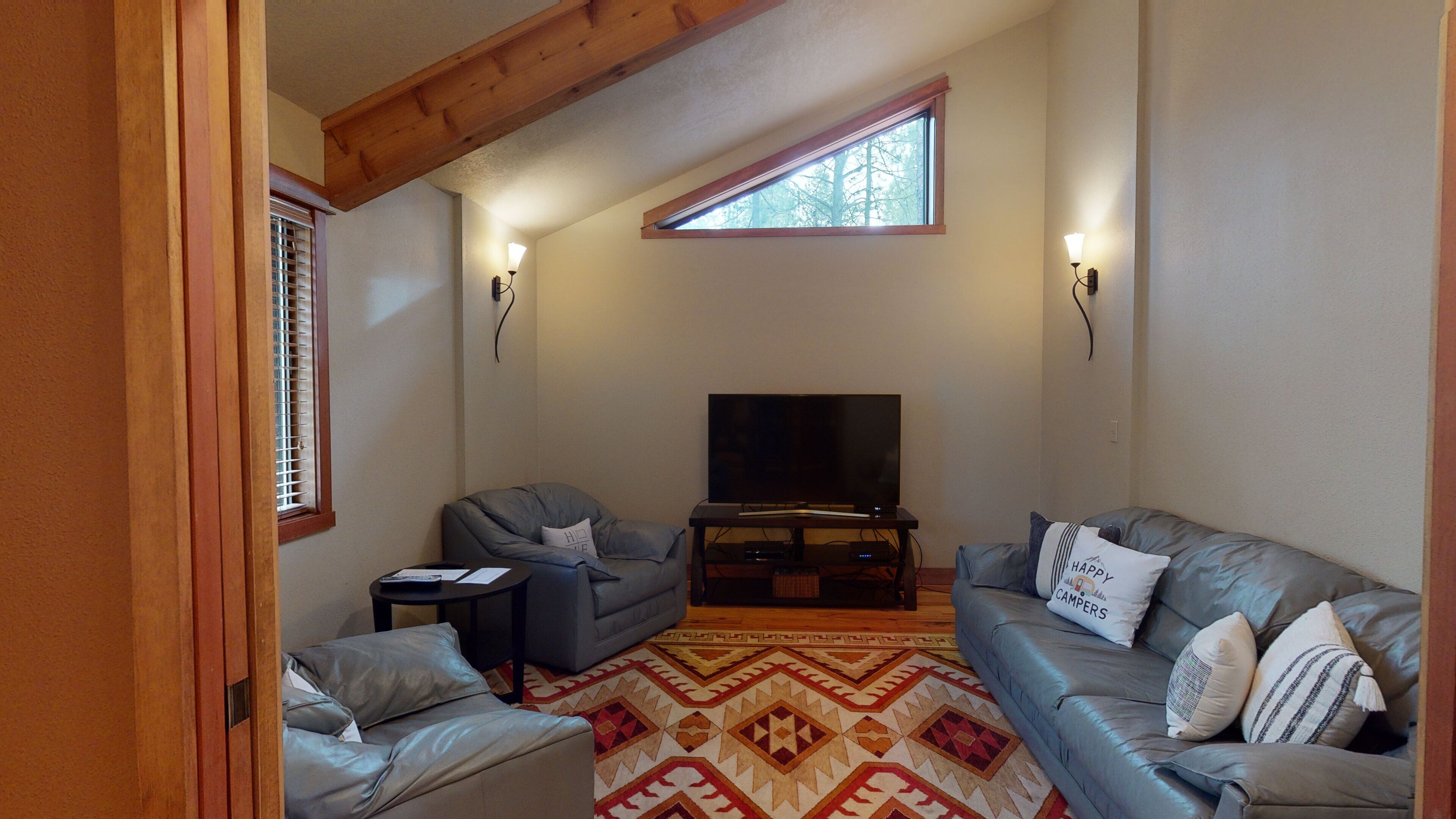 A living room with a television, two sofas, a coffee table, and a patterned rug.