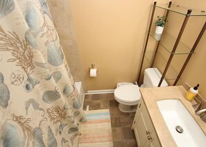 Ein Badezimmer mit Toilette, Waschbecken und Duschvorhang mit Meeresmotiv.