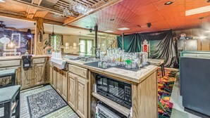 A kitchen with wooden cabinets, a central island with a sink, and a colorful rug.