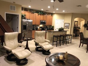 A spacious living room with a large sofa, a coffee table, and a dining area with bar stools.