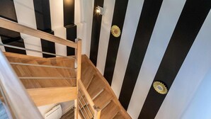 A wooden spiral staircase with black and white striped walls.