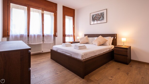 Una camera da letto ordinata con un letto, comodini, una scrivania e un termosifone.