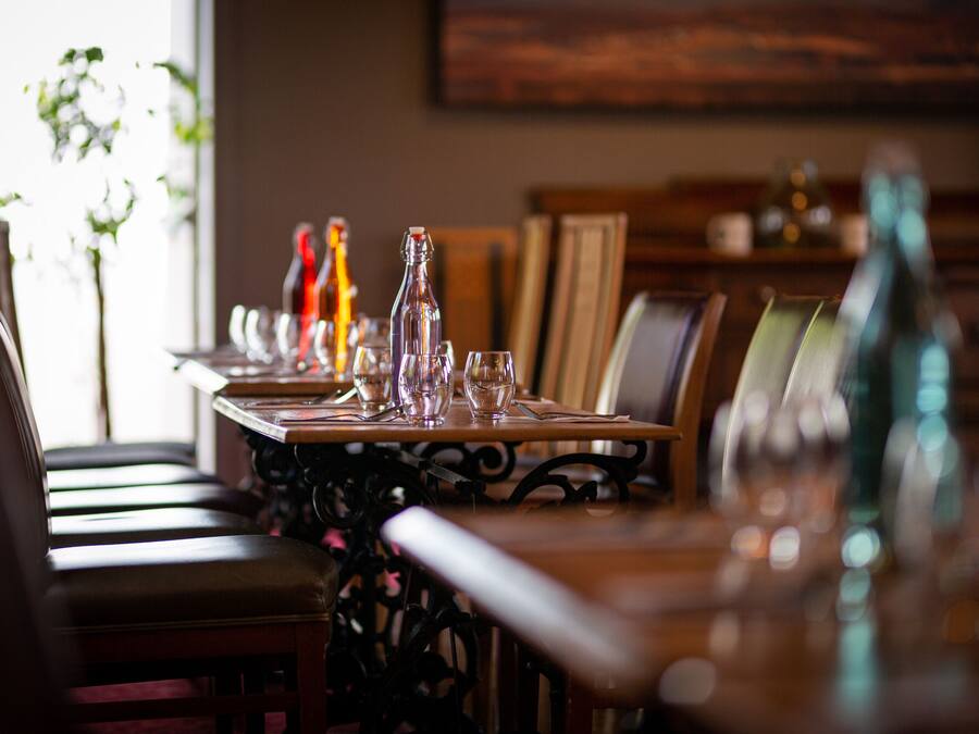 A dining table set with glasses and bottles, surrounded by chairs.