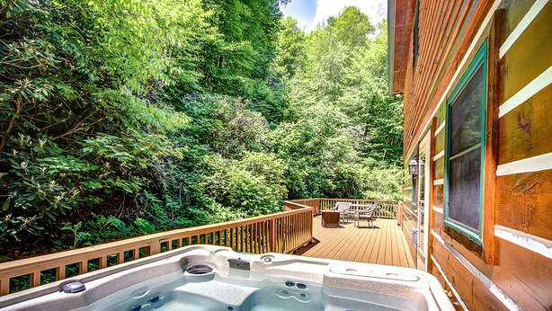 A hot tub on a wooden deck surrounded by lush greenery. - Closest cabin to Tweetsie. BEST Blowing Rock Location!  Hot tub & game room (Blowing Rock)