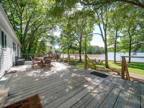 Eine Holzterrasse mit Gartenmöbeln, mit Blick auf einen See.