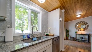 A modern kitchen with granite countertops, a stainless steel sink, and white cabinetry.