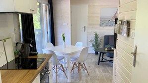 A modern kitchen with white cabinets, a wooden countertop, and a dining area with a white table and chairs. - Wassermann vacation home with box-spring beds and large terrace (Wunstorf)