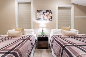 A hotel room with two beds, a nightstand with a lamp, and a floral artwork on the wall.