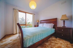 A bedroom with a bed, a nightstand, a lamp, a window with curtains, and a ceiling light.