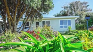 A single-story building with a light-colored exterior, surrounded by a variety of plants and trees. - 150  Steps to Beach with EV Charging (Apollo Bay)