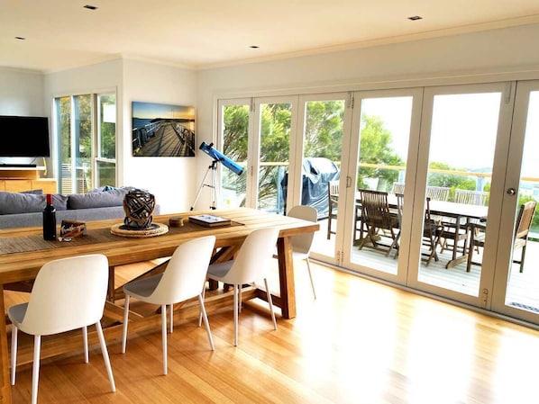 Un comedor moderno con una mesa y sillas de madera, un telescopio y un ventanal con vistas al exterior.