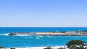 A coastal view with a rocky shoreline, clear blue sky, and a distant pier. - Apollo Ocean Blue Ocean View Wi-Fi Pet Friendly (Apollo Bay)