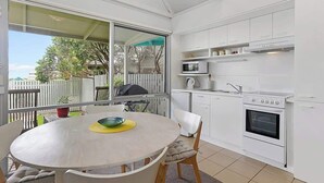 Una cocina con armarios blancos, microondas, estufa y una mesa de comedor con sillas.