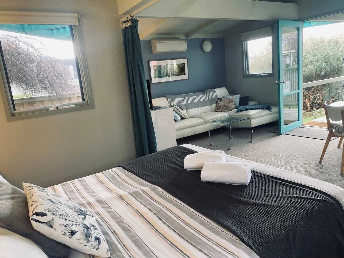 Ein Schlafzimmer mit Bett, Sofa, kleinem Tisch und Balkon.