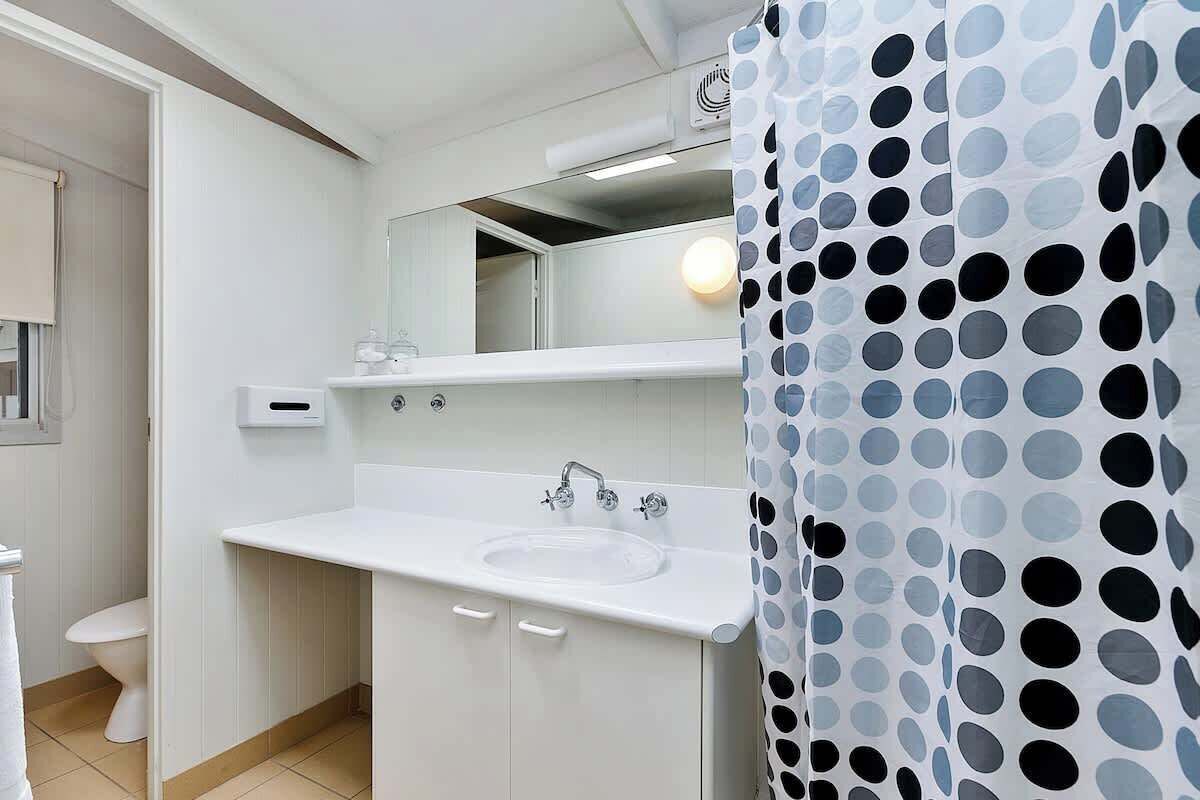 A bathroom with a white sink, mirror, and a shower curtain with a polka dot pattern.
