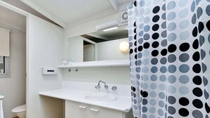 Un baño con lavamanos blanco, espejo y cortina de ducha con estampado de lunares.