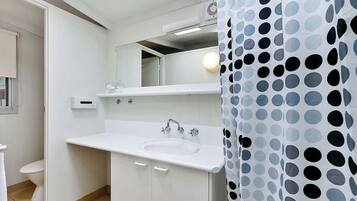 A bathroom with a white sink, mirror, and a shower curtain with a polka dot pattern.