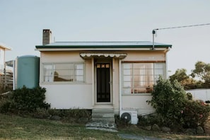 Simple, functional home with a flat roof and front porch, surrounded by a well-maintained lawn.