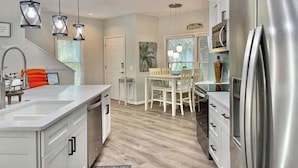 A modern kitchen with a central island, stainless steel appliances, and pendant lighting.
