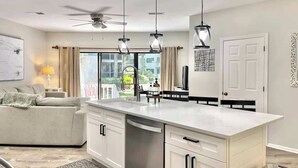 A modern kitchen with a central island, white cabinetry, and pendant lighting.