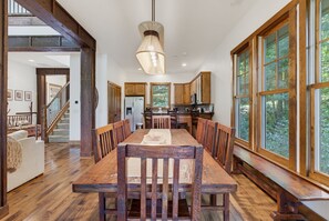 A spacious dining area with a wooden table and chairs, a hanging light fixture, and large windows offering a view of the outdoors. - 65 Southshore Drive Lodge 3 at Bear Lake Reserve (Tuckasegee)