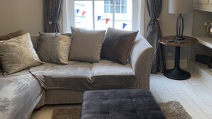 A living room with a sofa, ottoman, and a lamp on a table. - Impeccable 1-bed Apartment in the Heart of Hexham (Hexham)