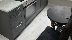 A modern kitchen with dark cabinets, a black countertop, and a window with blinds. - Impeccable 1-bed Apartment in the Heart of Hexham (Hexham)
