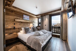 Un dormitorio con pared de madera, una cama con manta mullida, una mesita de noche y vistas al exterior.