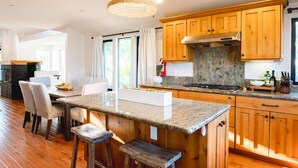 A modern kitchen with wooden cabinets, granite countertops, and a central island with bar stools. - Walk to the Beach/Rooftop Deck with Views/7 beds- 2 Kings/ A/C (Encinitas)