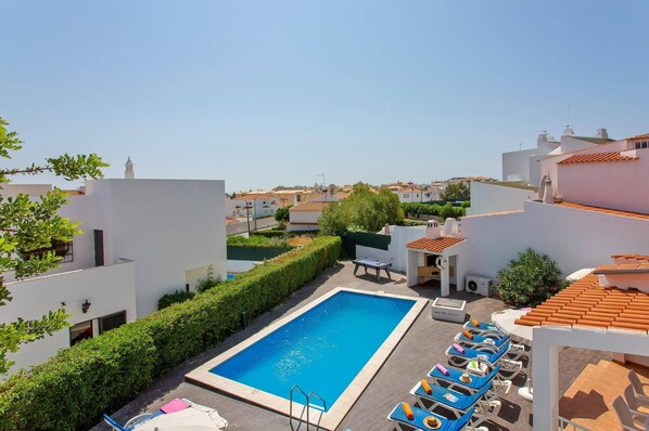 A rooftop pool with a clear view of the surrounding neighborhood, including white buildings and a clear sky.