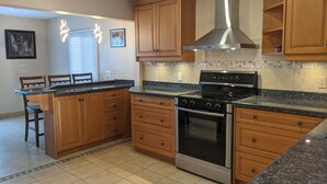 A kitchen with wooden cabinets, a stainless steel range hood, a Bosch oven, and a granite countertop. - Puslinch Lake Waterfront (Puslinch)