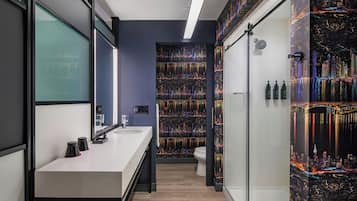 Un baño moderno con un espejo grande, un lavabo blanco y una ducha con cerramiento de vidrio.