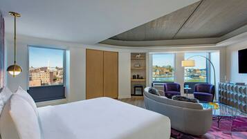 A hotel room with a bed, seating area, city view, and a television.