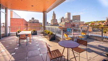 Una terraza en la azotea con mobiliario exterior, vistas a la ciudad y un diseño arquitectónico moderno.