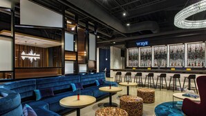 Un'area lounge moderna con sedute blu, tavolini rotondi e pouf decorati.
