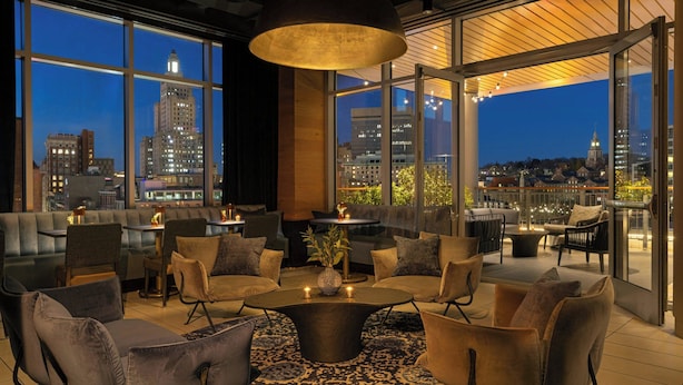 Un'area lounge moderna con un tavolino centrale, sedute confortevoli e ampie finestre con vista sulla città.