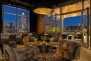A modern lounge area with a central coffee table, comfortable seating, and large windows offering city views. - Aloft by Marriott Providence Downtown (Providence)