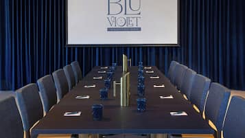 A conference room with a long table, chairs, and a screen displaying "BLU VOET ROOFTOP BAR".