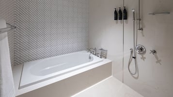 Une salle de bain moderne avec une baignoire sur pieds, une douche à l’italienne et un mur recouvert de carreaux.