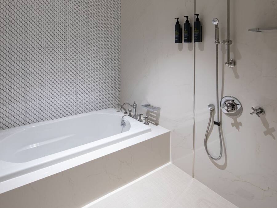 Une salle de bain moderne avec une baignoire sur pieds, une douche à l’italienne et un mur recouvert de carreaux.
