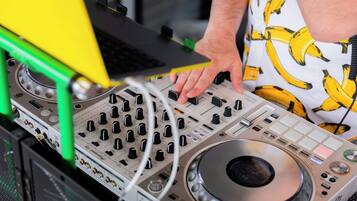 Une console de mixage pour DJ, dotée de nombreux boutons et potentiomètres, et reliée à un ordinateur portable et à du matériel audio.