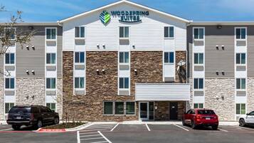 Un hotel de varios pisos con fachada de piedra y un letrero que dice 'Woodspring Suites'.