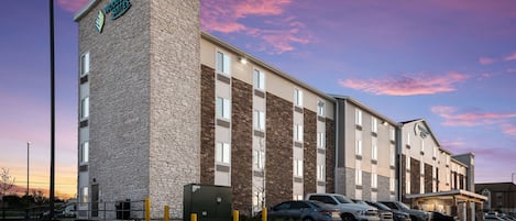 A hotel with a stone facade and multiple parking spaces.