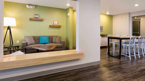Ein modernes Wohnzimmer mit Sofa, Couchtisch und Lampe. Es gibt einen Essbereich mit Tisch und Stühlen.